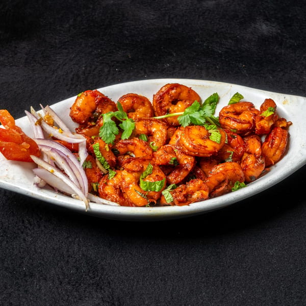 Anjappar Chettinad Indian Restaurant's spicy shrimp dish with red onions and cilantro in a white bowl.