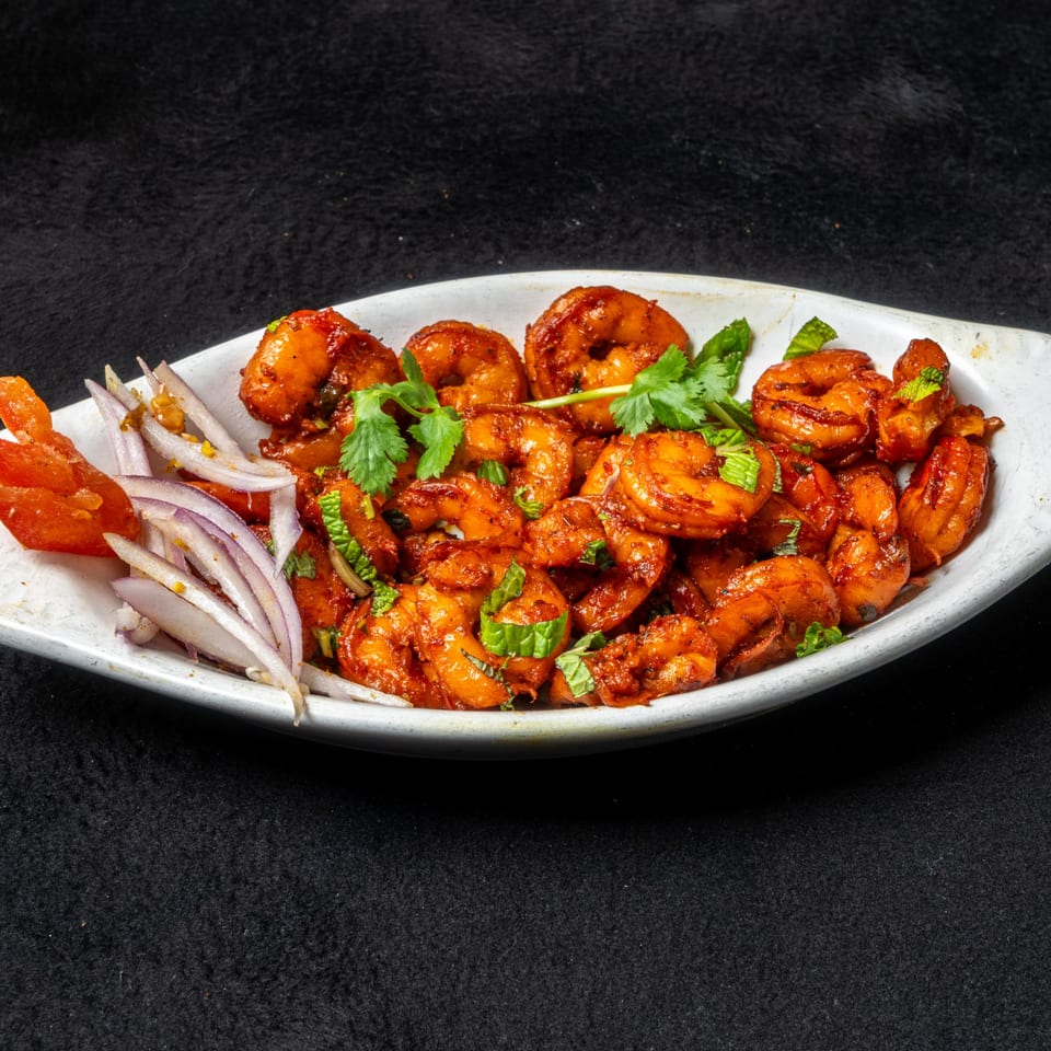 Anjappar Chettinad Indian Restaurant's spicy shrimp dish with red onions and cilantro in a white bowl.