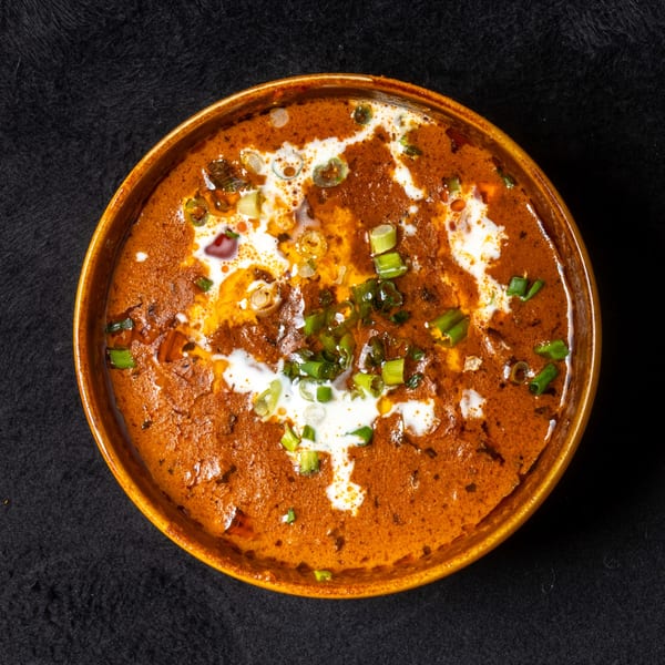 Anjappar Chettinad Indian Restaurant's orange curry dish with white cream swirls and green onions.