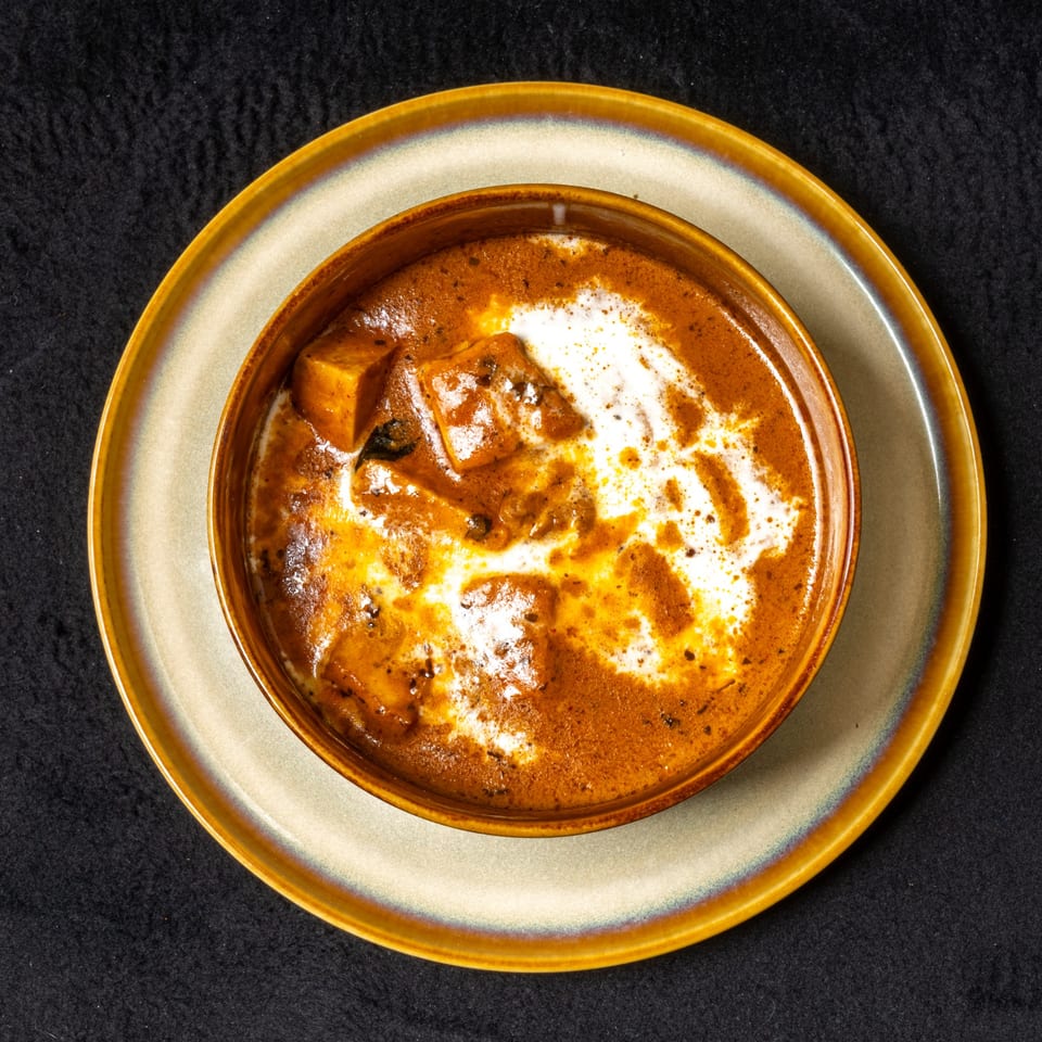 Anjappar Chettinad Indian Restaurant's paneer butter masala, a rich orange curry with white cream swirls.