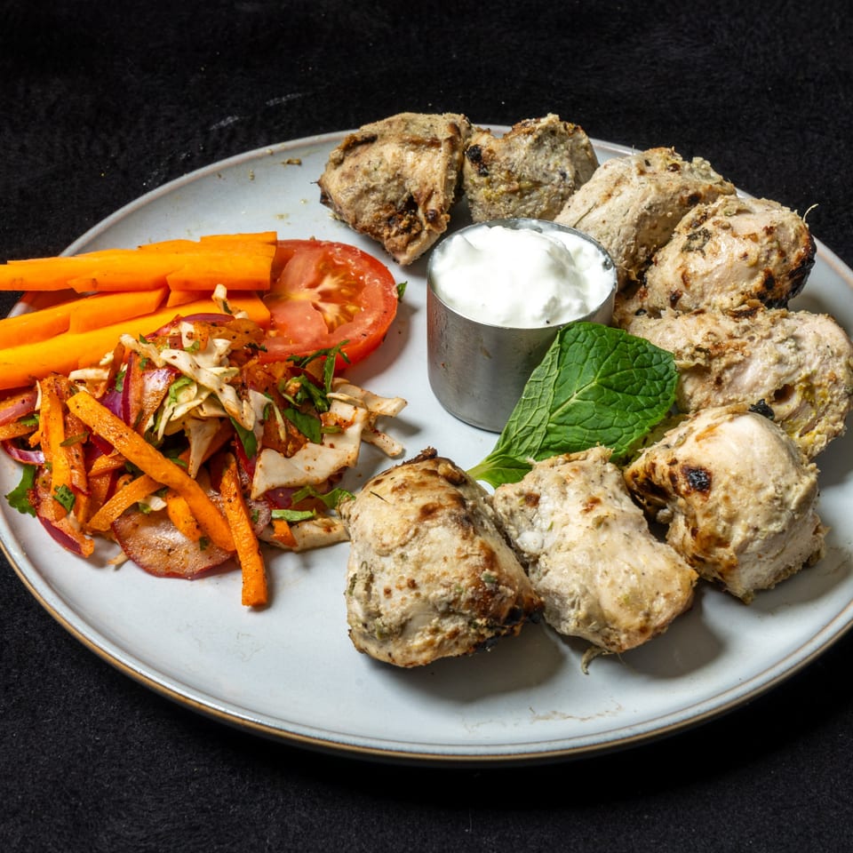 Anjappar Chettinad Indian Restaurant's grilled chicken tikka, salad, carrots, and yogurt dip on a plate.