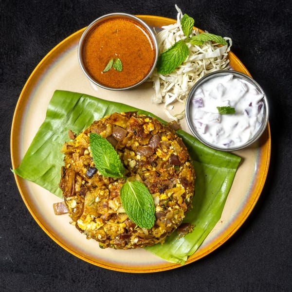 Anjappar Chettinad Indian Restaurant's Kothu Parotta, served with two sauces and shredded cabbage, garnished with mint.