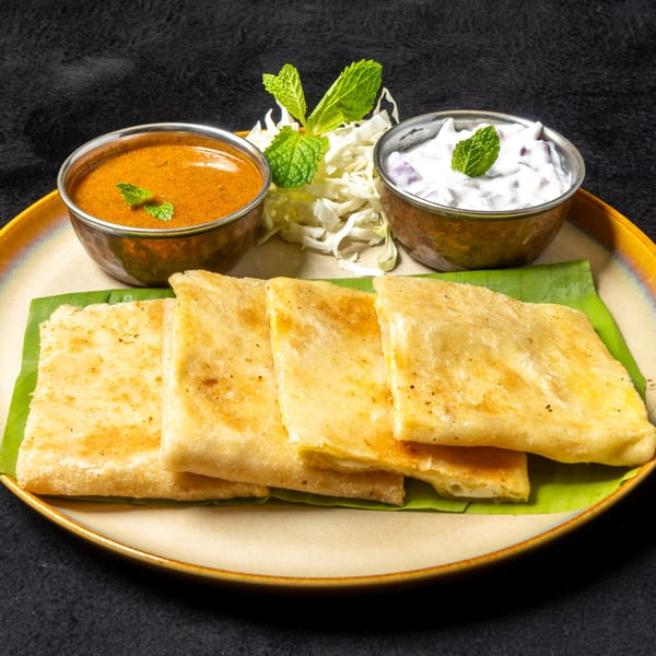 Anjappar Chettinad Indian Restaurant's dosa with two bowls of curry and raita, garnished with mint.