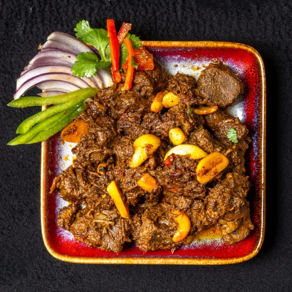 Anjappar Chettinad Indian Restaurant's dark brown curry with cashews, red onions, and green peppers.